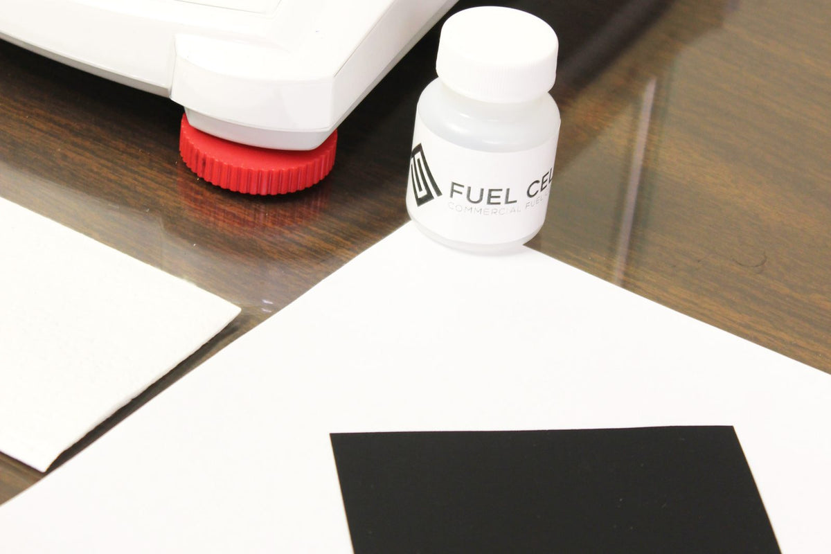 Sample bottle and black square gas diffusion electrode on a white sheet